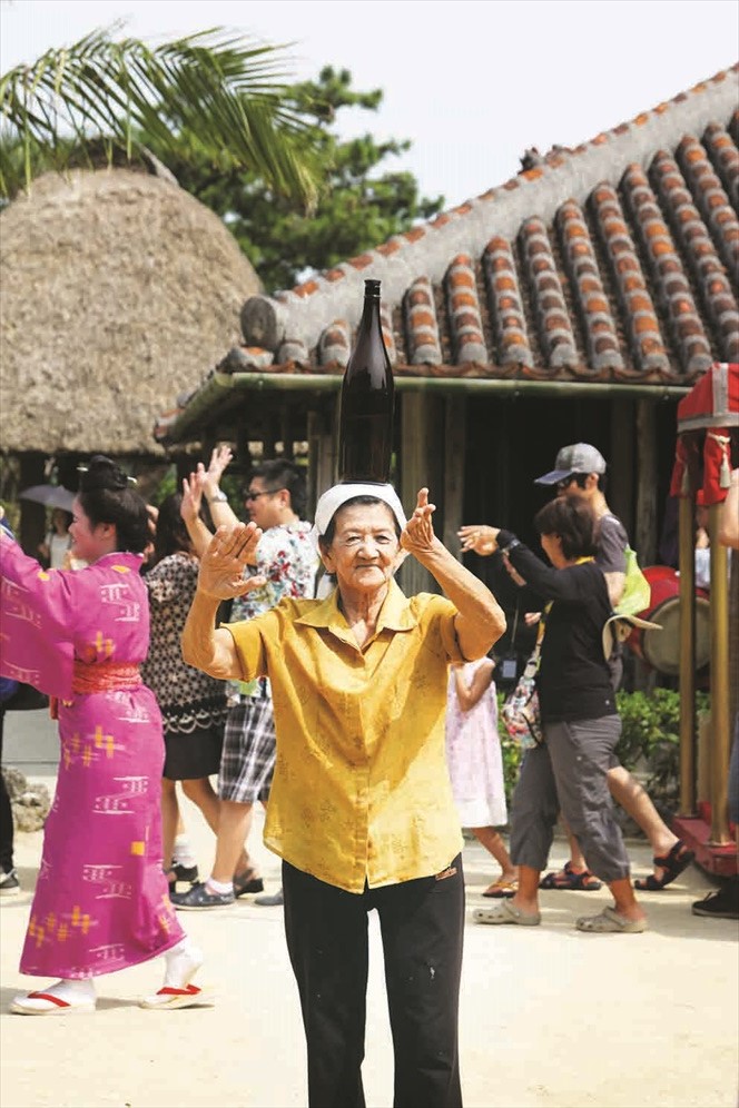 琉球村知名的老婆婆会顶着大酒瓶和游客一起跳舞。